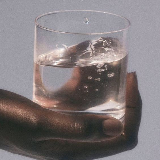 A hand holding a glass of water with bubbles.